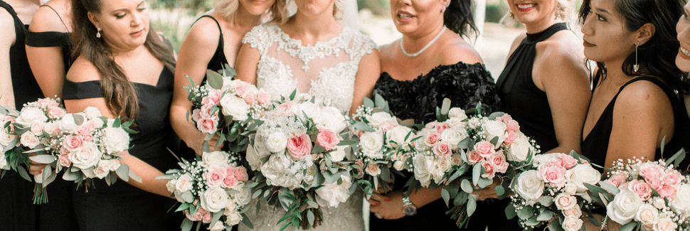 Bride and bridesmaids holding bouquets of pink and white roses with greenery and baby's breath, designed by Beneva Weddings in Sarasota FL